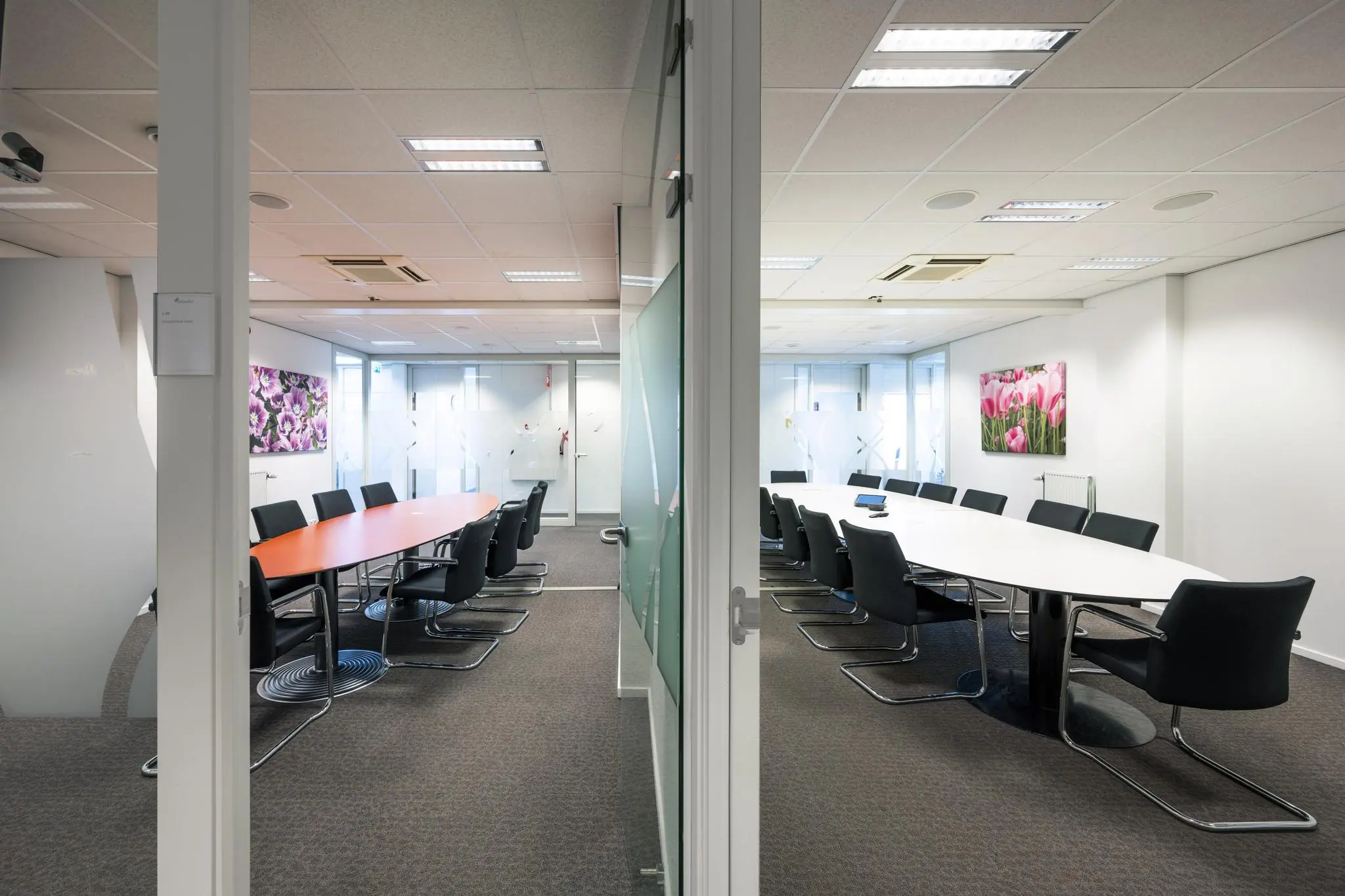 Twee moderne vergaderruimtes in een kantoorpand aan de Jan Tooropstraat, gescheiden door een glazen wand.